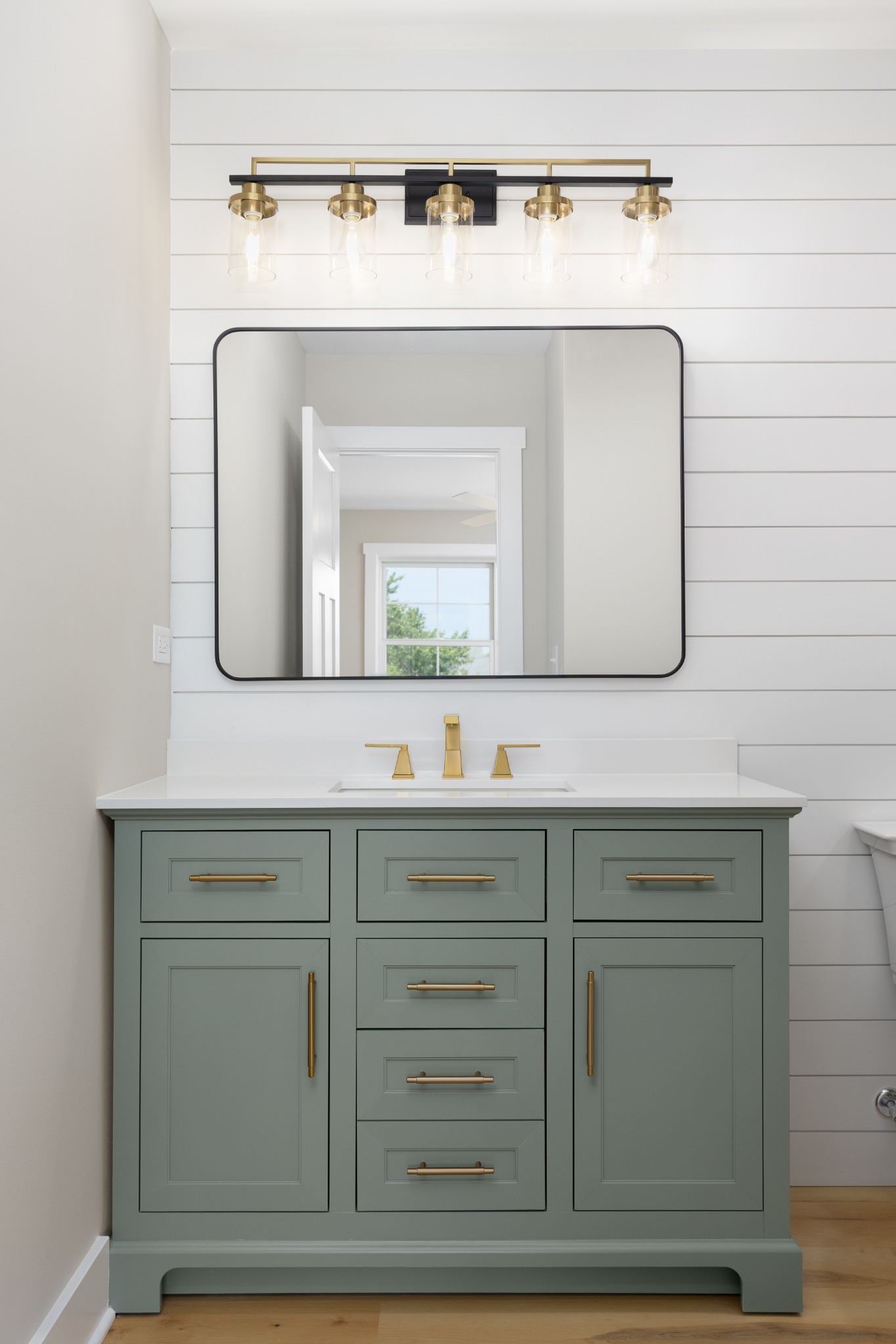 Green furniture-style bathroom vanity with marble countertop and framed mirrors