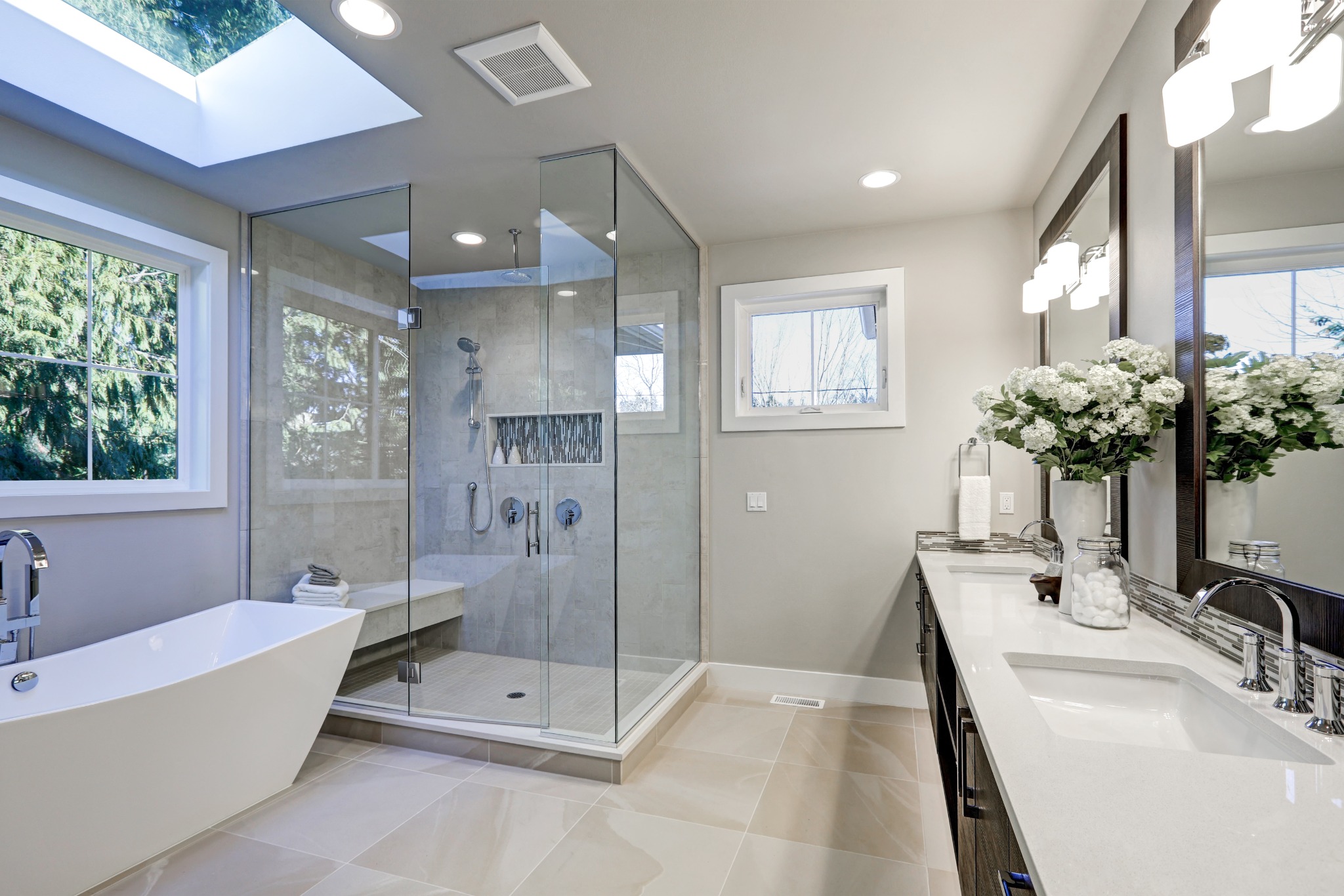 Bright residential bathroom with freestanding tub, glass shower and dark vanity