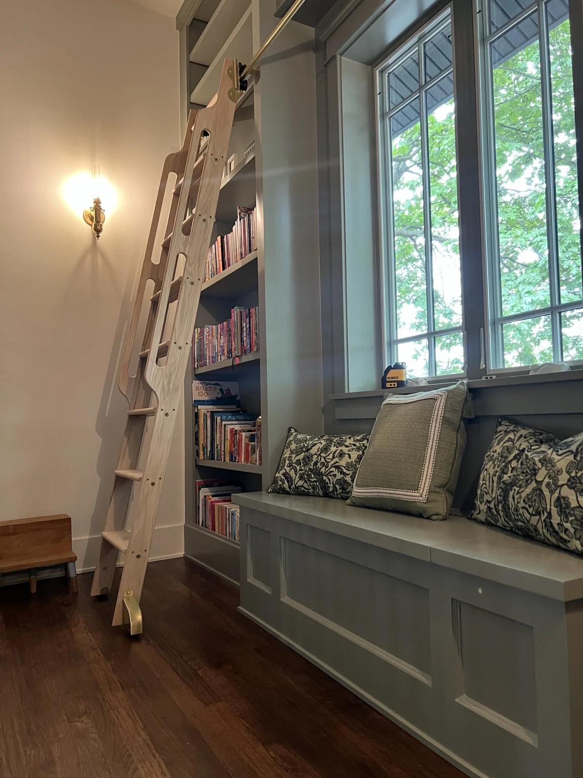 Built-in library shelving with rolling ladder and window seat